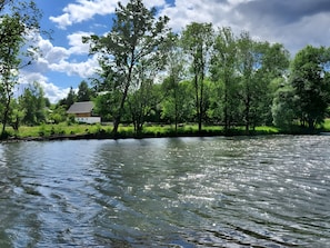 A river with trees and a house in the background.