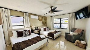 A hotel room with two beds, a TV, a ceiling fan, and a massage chair. - Pool+Spa+ 3.5 Baths+Outdoor Grill (Bradenton)