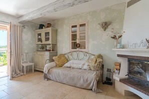 Une pièce comprenant un canapé, une armoire, une cheminée et une fenêtre décorée d’une guirlande.
