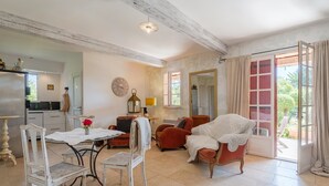 Una habitación con una mesa de comedor, sillas, un sofá, una silla con una manta, un espejo y una puerta que da a un espacio al aire libre.
