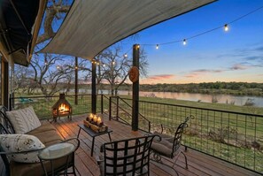 Une terrasse avec coin salon extérieur, un foyer et vue sur un lac.