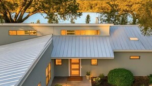 Une maison moderne à deux étages, dotée d’un toit en pente, d’une entrée principale et d’un petit jardin agrémenté d’une statue.