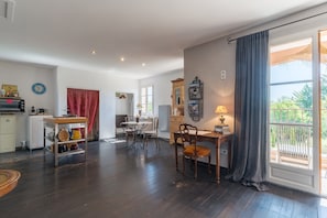 A spacious living area with a dining table, chairs, a TV, and a kitchen area with a microwave and cabinets.