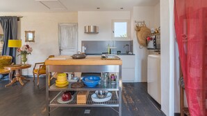 A compact kitchen with a central island, a dining area with a yellow chair, and a red curtain. - Holiday Home 'Lacoste Home' with Mountain View, Shared Pool and Wi-Fi (Lacoste)