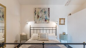 A bedroom with a bed, bedside tables, a mirror, and a wall art piece. - Holiday Home 'Lacoste Home' with Mountain View, Shared Pool and Wi-Fi (Lacoste)