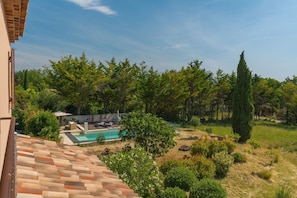 A residential area with a swimming pool, lush greenery, and a tiled roof.