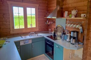 A kitchen with a window, a sink, a stove, and a coffee maker. - Time out in a log cabin/holiday home - peace and relaxation not far from the beach in Grömitz (Grömitz)