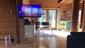 Un interior de fusta amb televisió, zona de menjador i cuina.