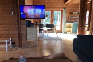 A wooden interior with a TV, a dining area, and a kitchen. - Time out in a log cabin/holiday home - peace and relaxation not far from the beach in Grömitz (Grömitz)
