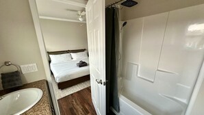 Een kleine kamer met een badkamer, een bed en een wastafel.