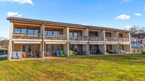 Un bâtiment à deux étages doté de balcons, d’une terrasse et d’une pelouse.