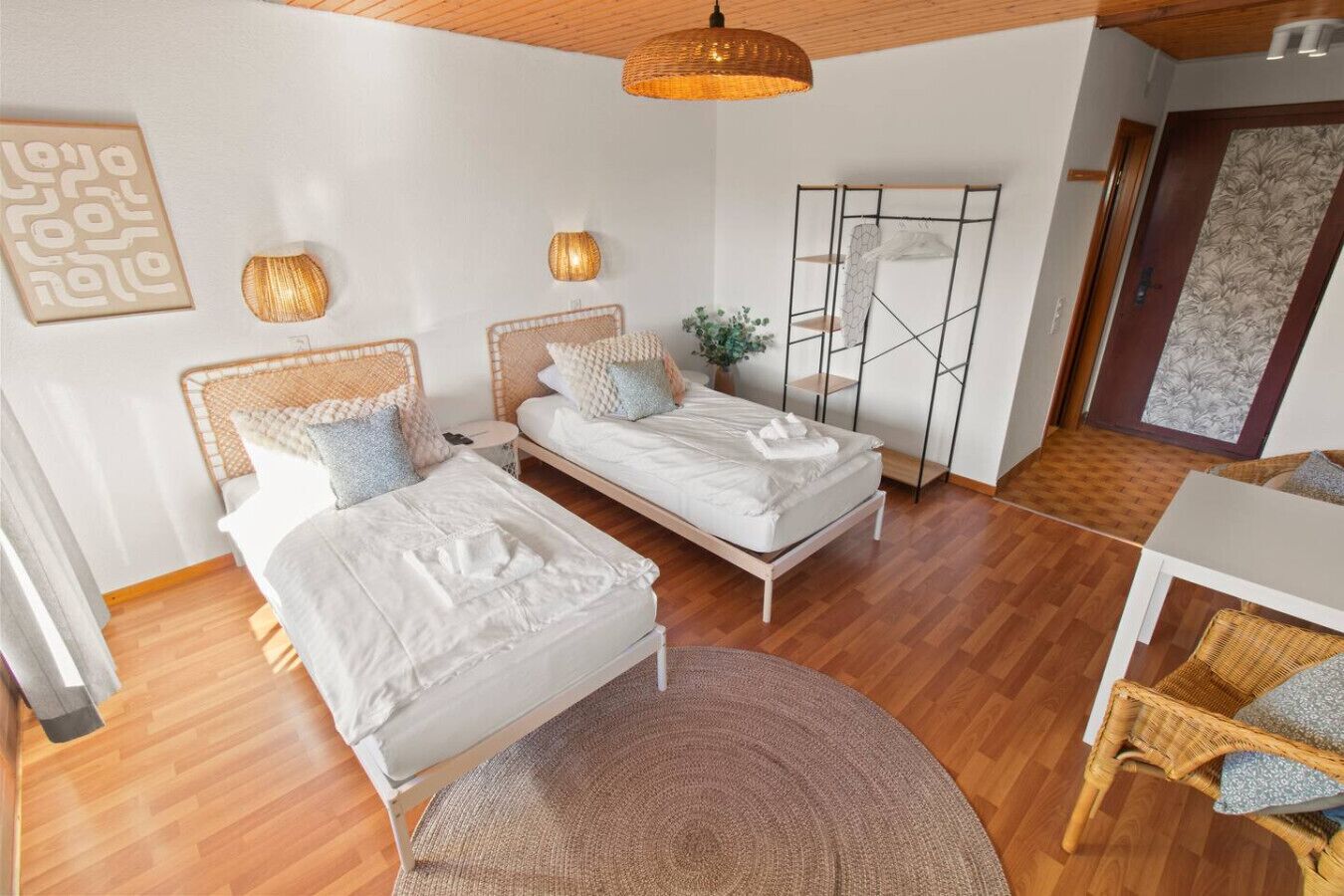 Une chambre moderne avec deux lits, un plafond en bois et une grande fenêtre.