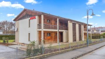 A two-story motel with a wooden facade, a balcony on the upper floor, and a fenced parking area.