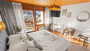 A bedroom with a large bed, a desk, and a chair.