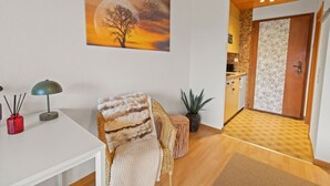Una sala de estar acogedora con chimenea, un comedor con mesa y sillas, y vista a la cocina por una puerta abierta.