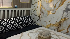 A bedroom with a bed, a decorative wall, and a ceiling light. - Misty Dream Condostay (Pasay City)