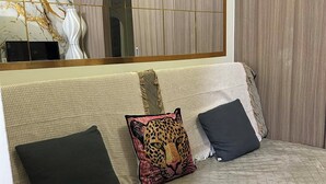 A modern living room with a sofa, two pillows, and a large mirror. - Misty Dream Condostay (Pasay City)