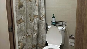 A small bathroom with a toilet, a shower curtain with a deer pattern, and a towel rack. - Misty Dream Condostay (Pasay City)