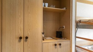 Une armoire en bois à deux portes, avec une étagère au-dessus.