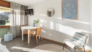 Ett modernt hotellrum med en matplats, en stor spegel, ett inramat konstverk och utsikt över omgivningarna.
