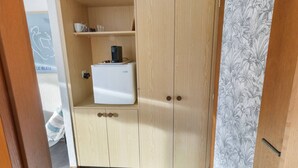 En garderob av trä med en liten hylla och en vit apparat, troligen ett minikylskåp, ovanpå.