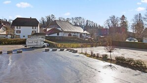 Un quartier résidentiel avec des maisons, un camping-car garé et une route bordée de bollards.