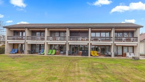 Un bâtiment à deux étages doté de balcons, d’une terrasse et d’une pelouse.