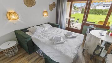 Une chambre bien rangée, avec un lit, des tables de chevet et une vue sur l’extérieur.