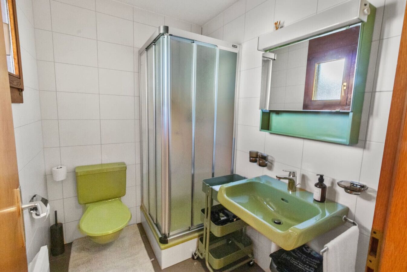 A bathroom with a shower, toilet, sink, and mirror.