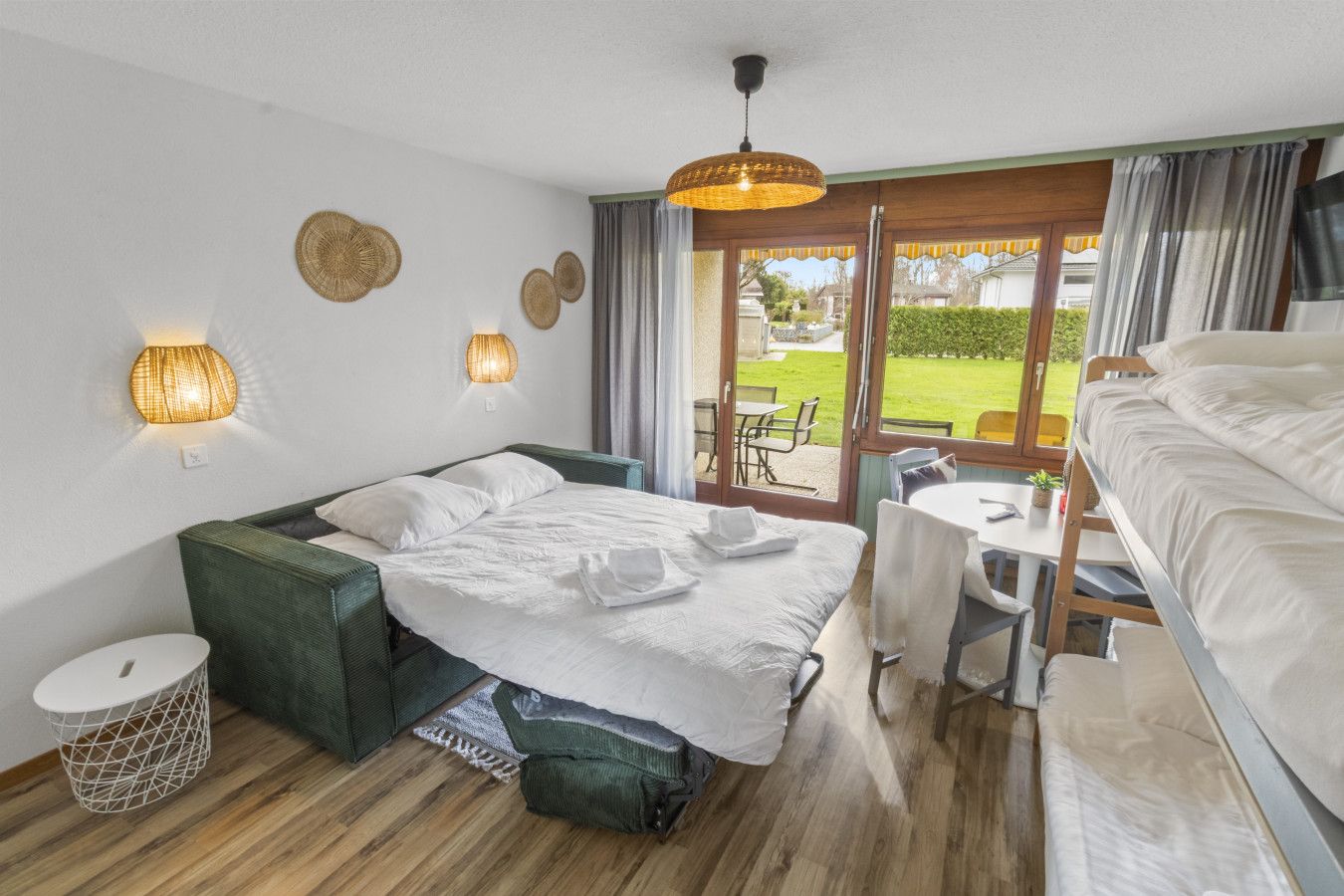 Quarto com cama, escrivaninha e vista para o exterior.