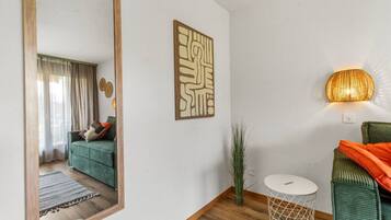 Uma sala de estar moderna com um sofá verde, uma mesa branca redonda e um objeto decorativo na parede.