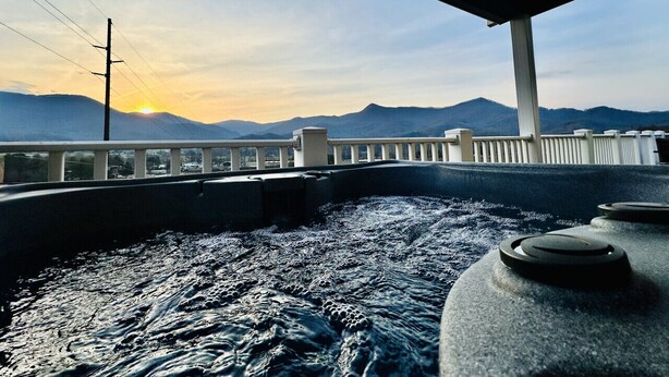 A view from a boat deck with a railing, water, and mountains in the background. - Seven Peaks Escape - Breathtaking 180°+ Mountain Views | 2 Hot Tubs (Waynesville)