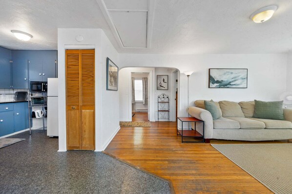A modern living space with a kitchen, a sofa, and artwork on the walls.