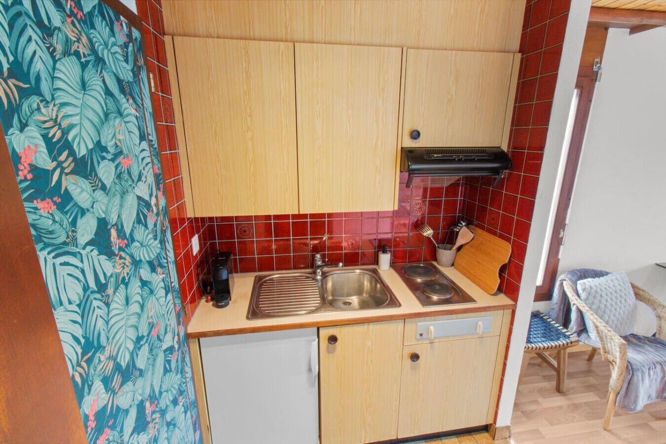 A compact kitchen with wooden cabinets, a stainless steel sink, and a small countertop.