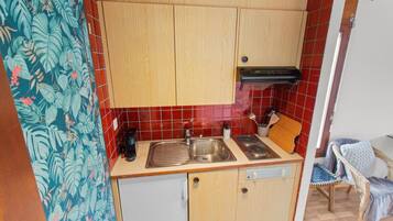 A compact kitchen with wooden cabinets, a stainless steel sink, and a small countertop.