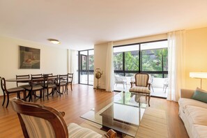 Amplia sala de estar con comedor, ventanas grandes y vistas al verde exterior.