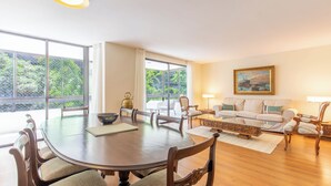Un salón amplio con una gran mesa de comedor, asientos cómodos y ventanas grandes que ofrecen vistas al verdor.