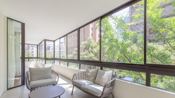 Un interior moderno con ventanas amplias, un sofá y una pequeña mesa.