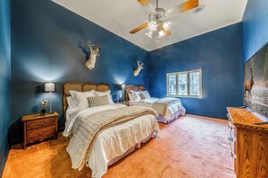 Een slaapkamer met twee bedden, een plafondventilator en aan de muur bevestigde hertenhoorns.