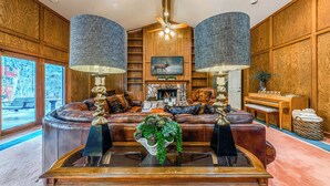 A spacious living room with a leather sofa, a fireplace, and a large window.