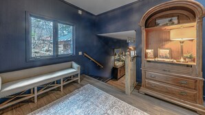 A room with a bench, a dresser, and a large window.