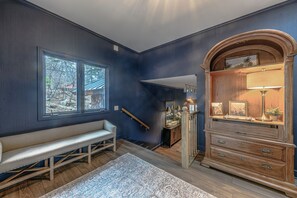 A room with a bench, a dresser, and a large window.