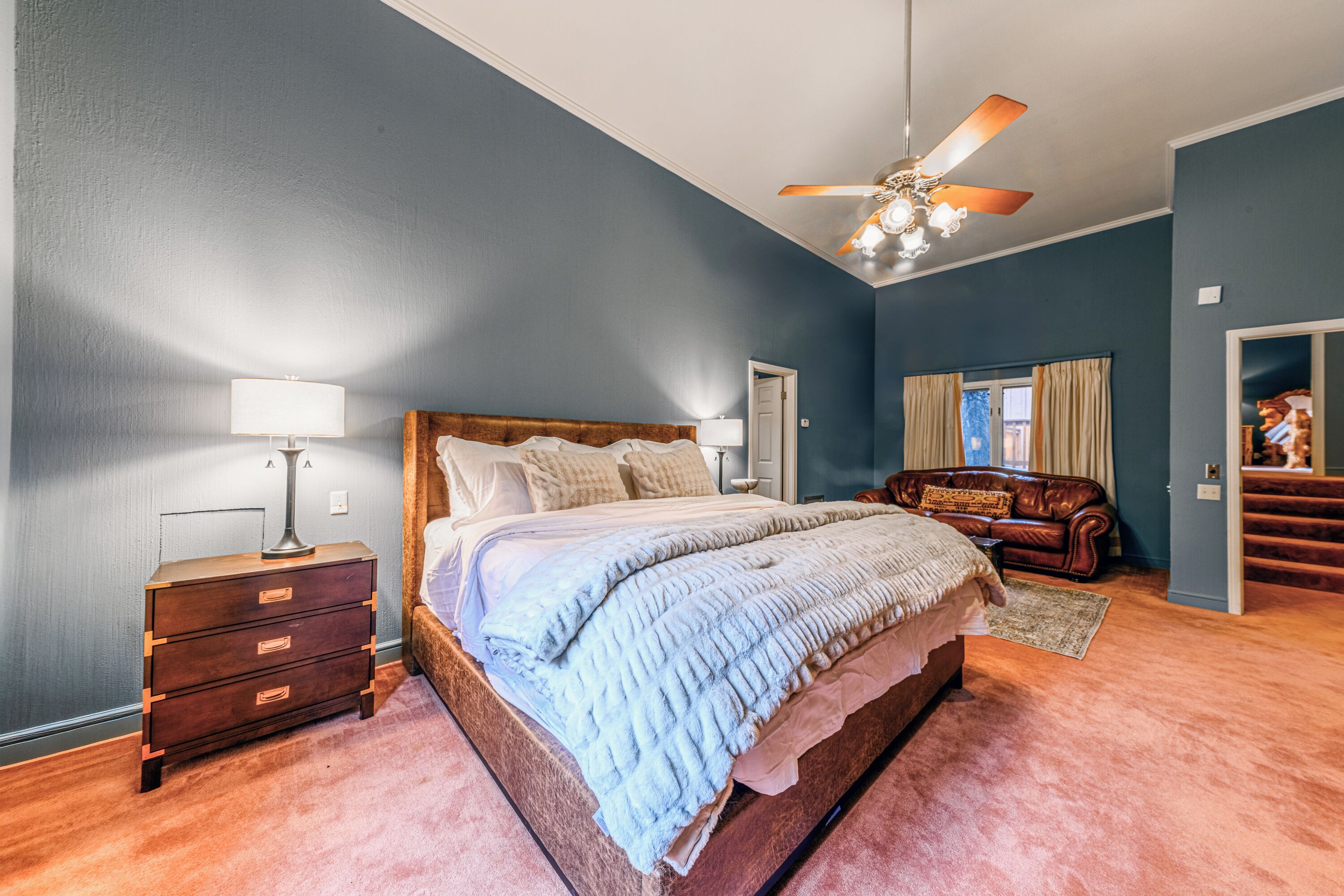 A bedroom with a bed, nightstand, dresser, and a ceiling fan.