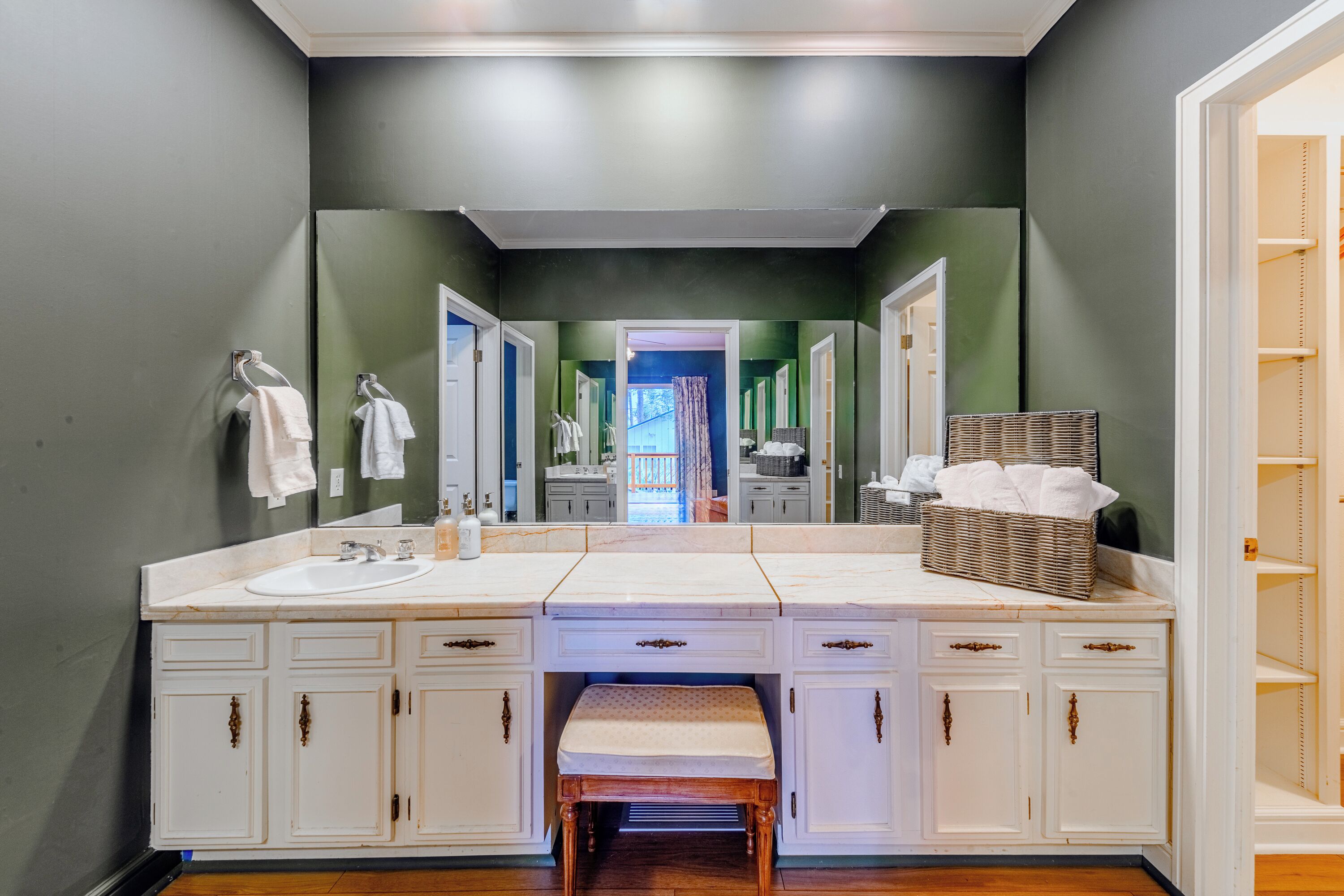 A bathroom with two sinks, a bench, and a basket of towels.