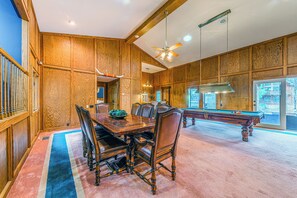 Ruime kamer met een pooltafel, houten lambrisering en een groot raam.