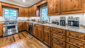 A kitchen with wooden cabinets, granite countertops, stainless steel appliances, and a window providing natural light.