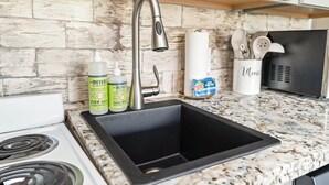 A kitchen with a black sink, a stainless steel faucet, a white stove, and a granite countertop. - Studio South (On UT Campus & Free Parking) (Knoxville)