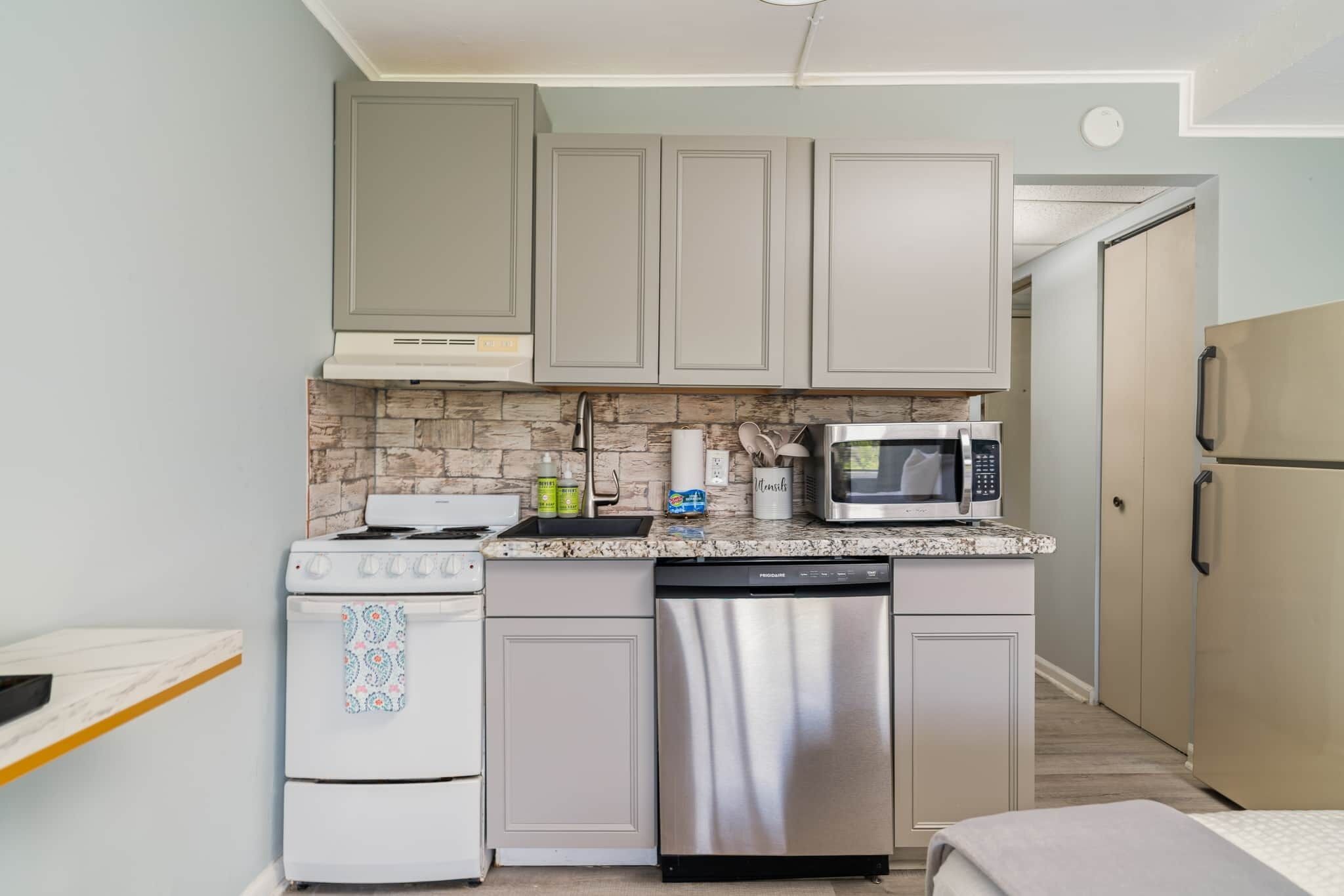A compact kitchen with a stove, microwave, dishwasher, and a small countertop.