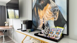 A room with a large framed painting of a dog, a coffee machine, a tray with snacks, and a table with a vase and a plant. - Studio South (On UT Campus & Free Parking) (Knoxville)