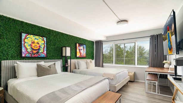 A modern hotel room with two beds, a desk, a TV, and artwork on the walls. - Studio South (On UT Campus & Free Parking) (Knoxville)
